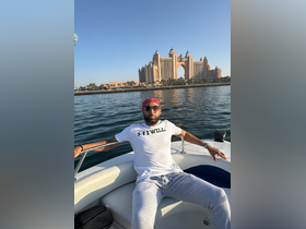 A man relaxes on a boat with the iconic Atlantis resort in the background, showcasing a perfect day on the water in Dubai.