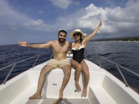 A joyful couple enjoys a sunny day on a boat, celebrating their time on the ocean with smiles and excitement — perfect for romantic getaways or fun adventures.