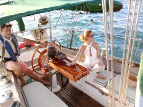 A stylish couple enjoys the helm of a sailboat, showcasing the cozy interior and inviting atmosphere perfect for a day on the water.