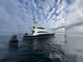 A sleek yacht with people on board navigates the ocean under a dramatic sky, perfect for fishing adventures and ocean exploration.