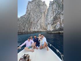 A cheerful group enjoys their time on a boat, surrounded by stunning rocky cliffs — perfect for memorable celebrations and scenic adventures on the water.