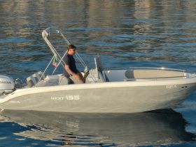 A man navigates a sleek boat on calm waters, showcasing the perfect day for boating adventures.