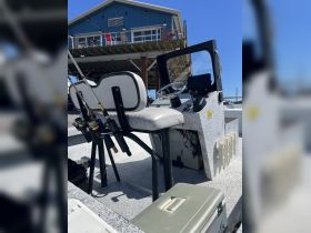 A well-equipped helm area of a fishing boat featuring comfortable seating and fishing rods, perfect for a day out on the water.