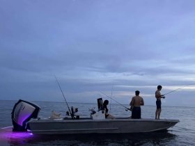 A group of friends enjoys an evening fishing trip on a boat, showcasing the perfect blend of relaxation and adventure on the water.