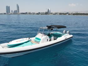 A sleek speedboat glides through clear waters with a stunning city skyline in the background, perfect for exploring coastal destinations.