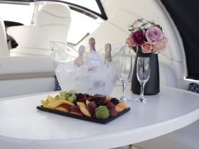 A beautifully arranged platter of fresh fruit and champagne on a boat table, perfect for a luxurious day on the water.