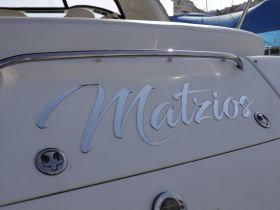 Close-up of the name 'Matzios' displayed on the back of a boat, showcasing its sleek design and branding.