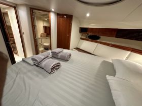 A cozy cabin interior featuring a neatly made bed with rolled towels, showcasing the comfortable amenities available on board.