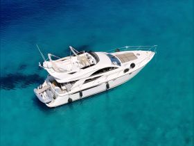 A stunning aerial view of a luxurious yacht cruising through crystal-clear turquoise waters, perfect for upscale charters and island adventures.