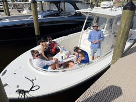 A lively group enjoys drinks and good times aboard a boat at the dock, perfect for a fun day on the water with friends.