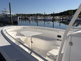 A spacious interior view of a boat's seating area, showcasing comfortable seating and a table, perfect for relaxing while docked at the marina.