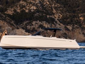 A stylish yacht glides through the water with a guest enjoying the view, set against a stunning rocky backdrop — perfect for luxury outings and scenic adventures.