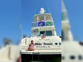 A young girl poses on the deck of the yacht 'Mila Yenin' in Pensacola, FL, showcasing a perfect day on the water.