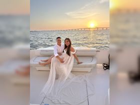 A couple enjoys a romantic sunset on a boat, capturing a perfect moment of love and celebration against a stunning backdrop.