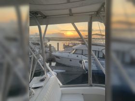 A serene view from inside the cabin of a boat, showcasing a beautiful sunset over the marina — perfect for relaxing moments on the water.