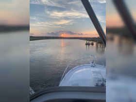 A stunning sunset view from the bow of a boat, showcasing tranquil waters and a picturesque horizon — perfect for evening cruises.
