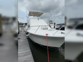A sleek yacht docked at the marina, showcasing its elegant design and structure against a cloudy sky.