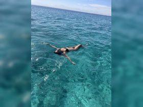 A woman floats serenely in crystal-clear waters, embodying the ultimate relaxation experience in a tropical paradise.