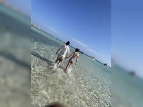 A couple walks hand-in-hand through the shallow waters of a beautiful beach, creating a romantic atmosphere perfect for memorable moments.