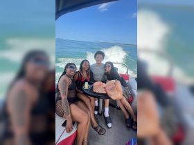 A lively group of friends enjoys a fun day on the water, capturing memories aboard a boat with beautiful scenery in the background.