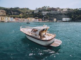 A beautiful boat glides through clear waters, with a picturesque coastal town in the background, showcasing the charm of seaside adventures.