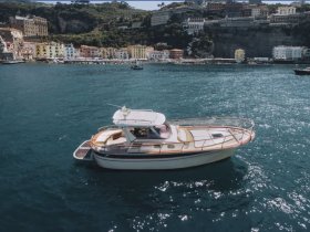 A beautiful yacht glides through the sparkling waters, showcasing its elegant design against a picturesque coastal backdrop.