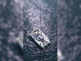 A stunning aerial view of a catamaran sailing through shimmering waters, showcasing a relaxing day on the water with guests enjoying the sun.