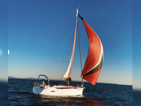A beautiful sailboat with a vibrant red sail glides through the water, showcasing the thrill of sailing on a clear day.
