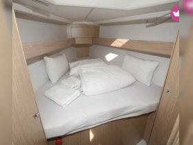 Cozy cabin interior featuring a neatly made bed with pillows and linens, perfect for restful nights on the water.