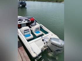 A young boy sits at the helm of a small boat, showcasing the interior seating and controls — perfect for a day of exploration on the water.
