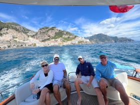 A cheerful group enjoys a scenic boat ride along the Amalfi Coast, capturing the stunning coastal views and the joy of being on the water.