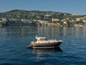 A beautiful yacht is anchored in calm waters, showcasing its elegant design against a stunning coastal backdrop.
