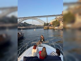 A group of friends enjoys a scenic boat ride, capturing memories against the backdrop of a stunning bridge and riverside views.
