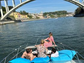 A group of friends relaxes on the bow of a boat, enjoying the scenic views of the city and bridge — perfect for a day out on the water.