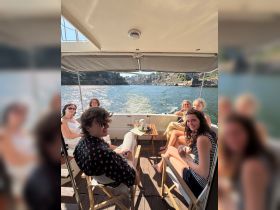 A lively group enjoys a sunny day on a boat, sharing drinks and laughter while cruising through scenic waters — perfect for gatherings and celebrations.