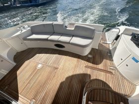 A cozy seating area inside a boat, featuring elegant wooden flooring and comfortable cushions, perfect for relaxing while cruising.