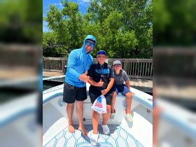 A joyful group of three, including two children, poses on a boat, all giving thumbs up — a perfect snapshot of family fun on the water.