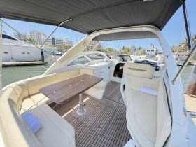A spacious and well-appointed interior of a boat featuring comfortable seating and a dining area, perfect for relaxing while enjoying the views at the marina.