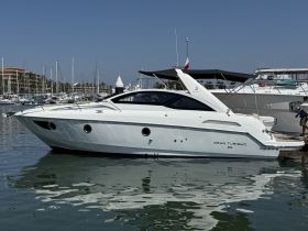 A sleek Gran Turismo yacht docked in a marina, showcasing its elegant design and reflective water surface — perfect for luxury boating experiences.