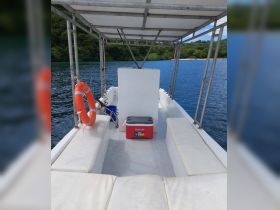 Interior view of a boat showcasing comfortable seating and a cooler, perfect for relaxing during a day on the water.