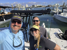A cheerful group of friends poses on their fishing boat, ready for a day of adventure on the water. Perfect for capturing the spirit of camaraderie and fun during a fishing trip.