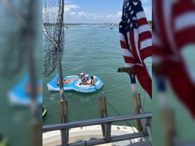 A group enjoys a sunny day on a floating mat in the water, showcasing the perfect summer fun experience on the water.