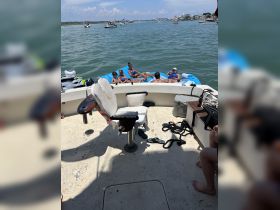 A lively group enjoys a sunny day on the water, relaxing on floating mats while anchored near their boat — perfect for summer fun and family outings.
