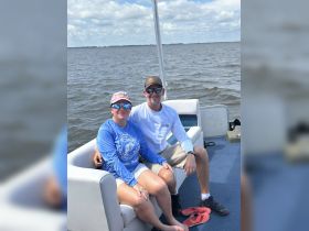 A cheerful couple enjoys their time on a boat, capturing the essence of a fun day on the water.