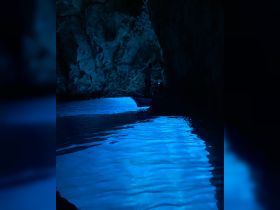 A captivating scene inside a cave with a boat navigating through stunning blue waters, showcasing the beauty of nature and adventure on the water.