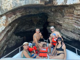 A cheerful family enjoys a boat trip inside a cave, showcasing fun and adventure on the water while wearing life jackets for safety.