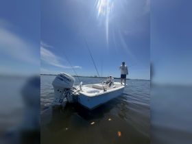 A fisherman stands on a boat while another prepares for a fishing adventure on calm waters, showcasing the thrill of outdoor fishing experiences.