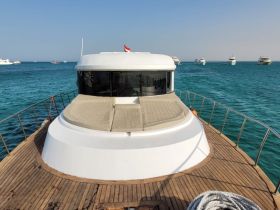 A stunning view of the back of a yacht docked in clear turquoise waters, showcasing its sleek design and inviting deck space.