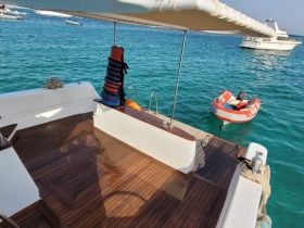 A serene view of the interior deck of a boat, showcasing the wooden flooring and safety gear, perfect for relaxing on the water.