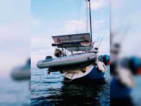 A striking view of a sailboat anchored in calm waters, showcasing its unique design and structure against a serene sky.
